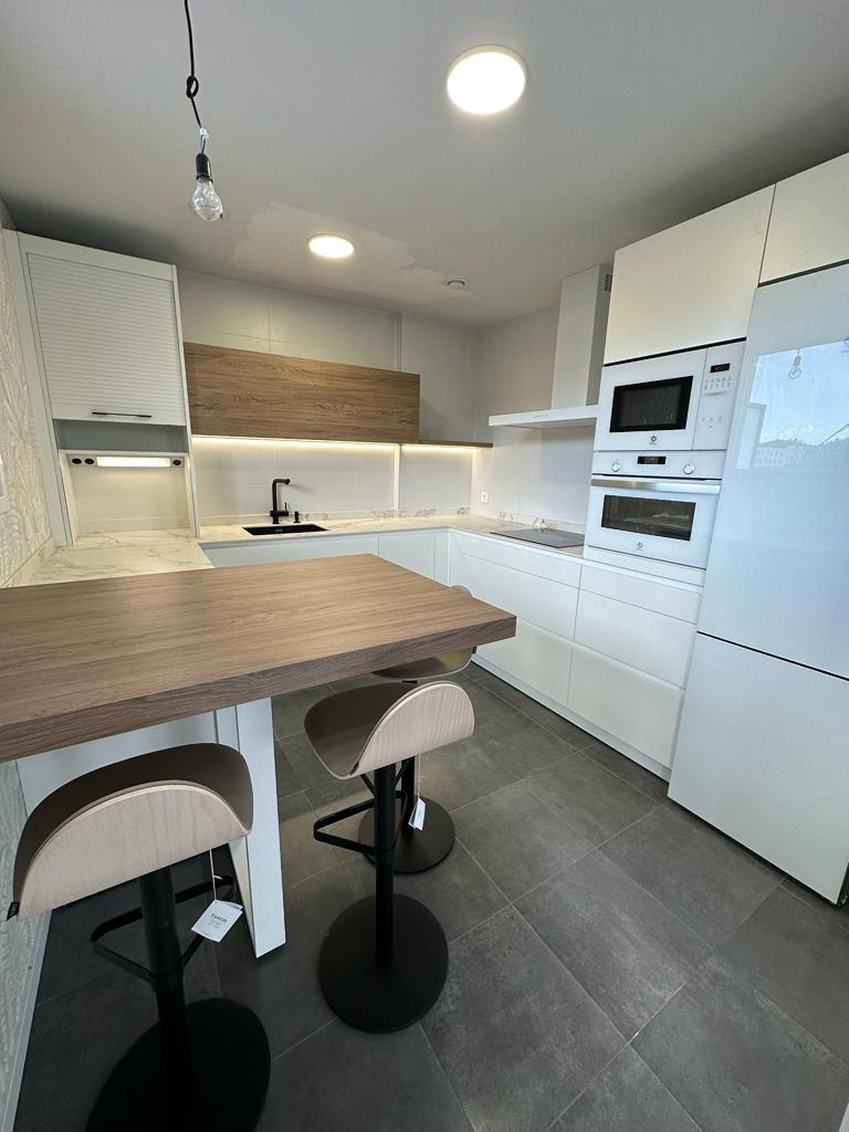 Cocina blanca mate con toques de madera y encimera Dekton.