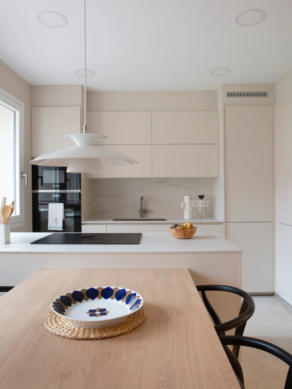 Península iluminada por luz natural Península con encimera Dekton Rem frente a dos ventanas y zona de aguas con grifo inox