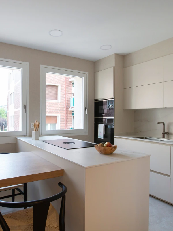 Península con placa BORA y cerramiento de vidrio Península beige con placa de inducción BORA y cerramiento de vidrio con perfil negro al fondo